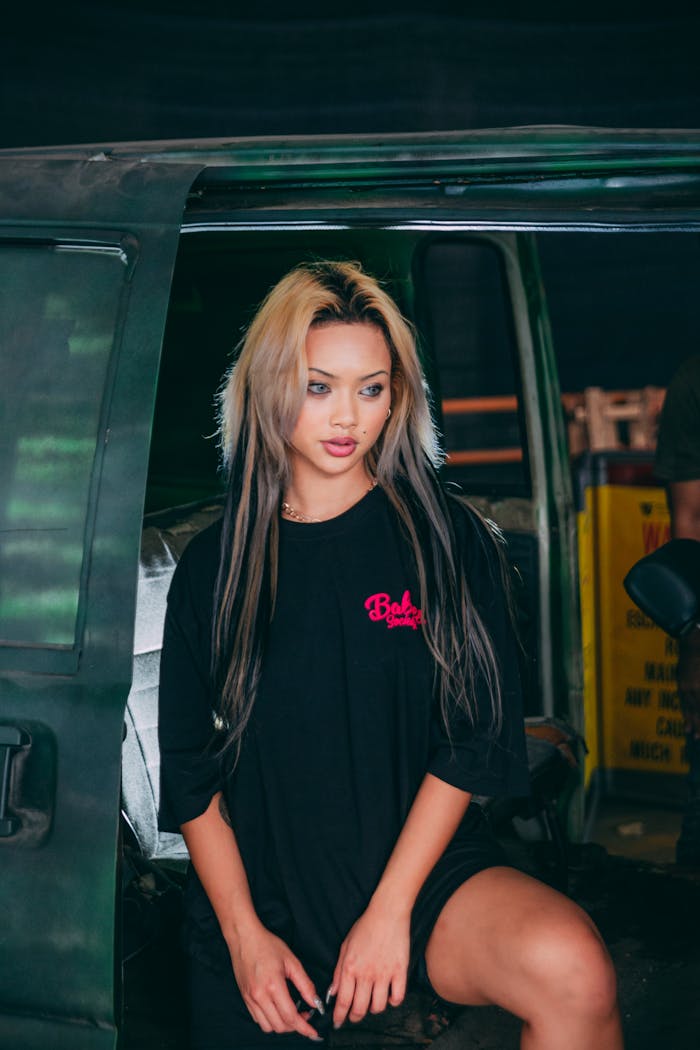 Portrait of a fashionable woman posing by a car in an urban environment, showcasing trendy style.