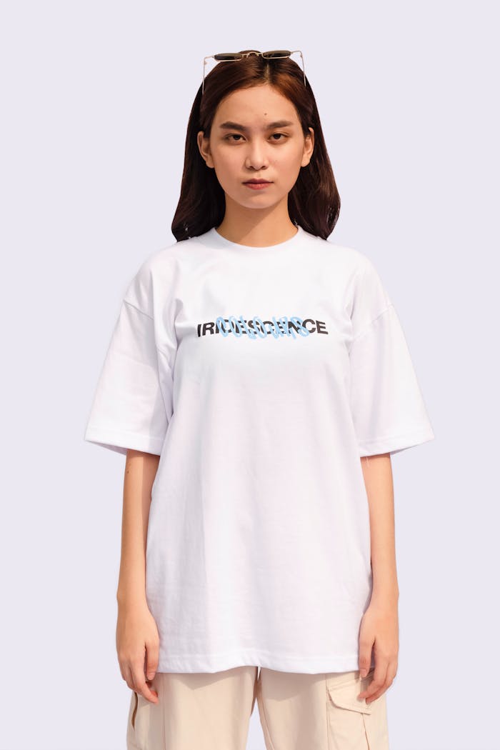 A young woman wearing a white t-shirt with iridescence text, standing confidently. Ideal for fashion and lifestyle themes.