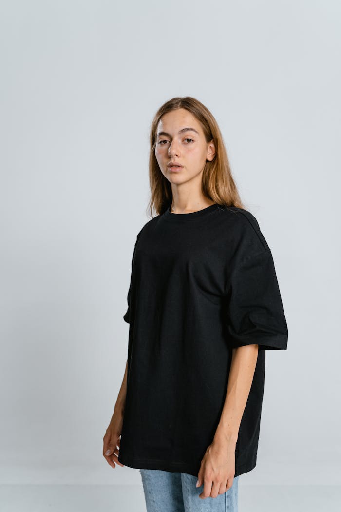 Portrait of a young woman in a black oversized t-shirt against a white background.